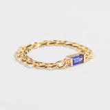 Gold chain ring with a rectangular blue gemstone centerpiece on a plain white background