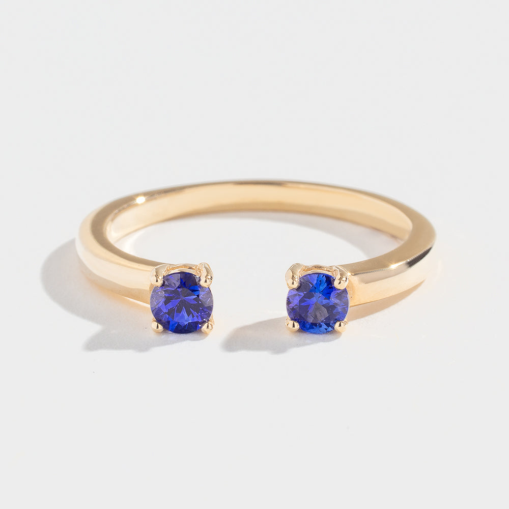 Gold ring with two round blue gemstones set on open ends