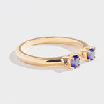 Gold ring with two round blue gemstones set on open ends