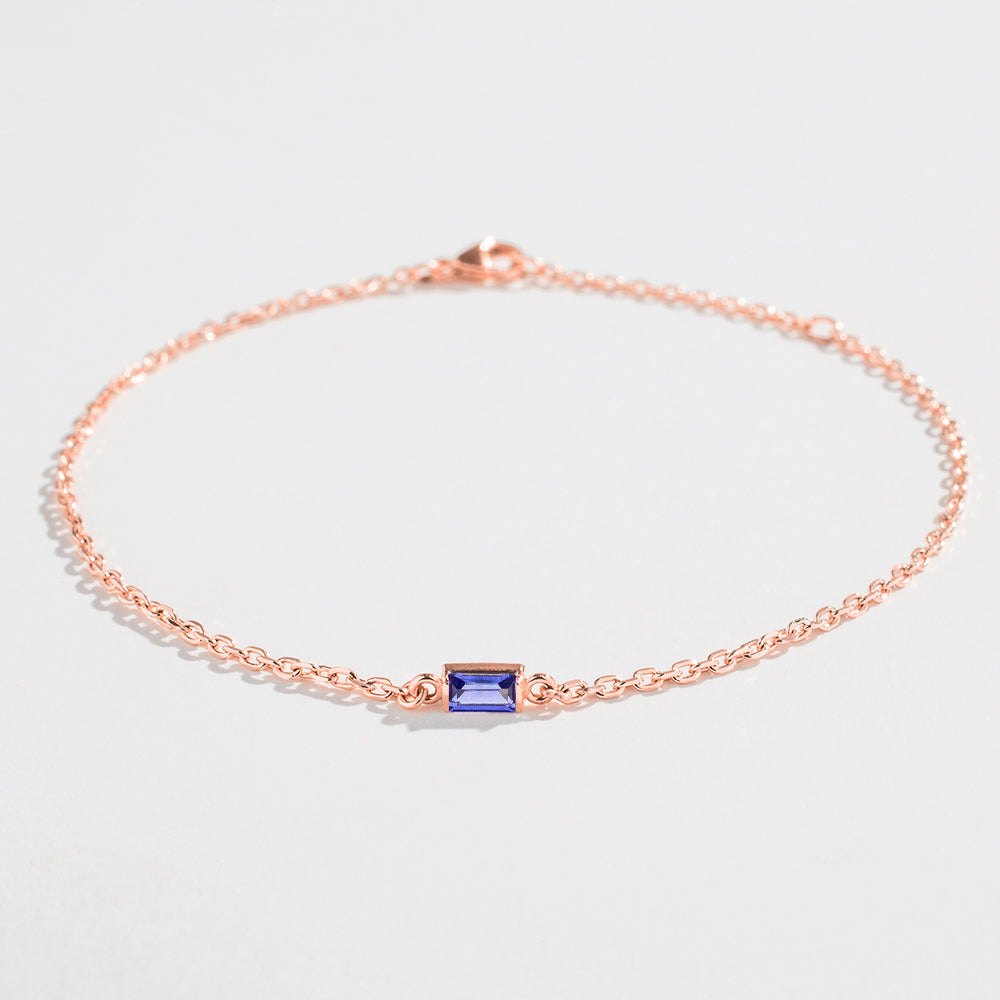 Rose gold bracelet featuring a rectangular blue Tanzanite gemstone at the center.