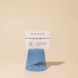 Blue bracelet with white description card on beige background reads "protection and Karma - flow of communication - calm and relaxation - courage" 